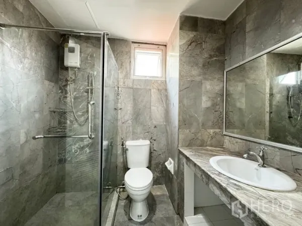 Townhouse for rent or sale in Suan Luang, Bangkok - Bright bathroom with gray marble tiles, glass shower, and long vanity mirror