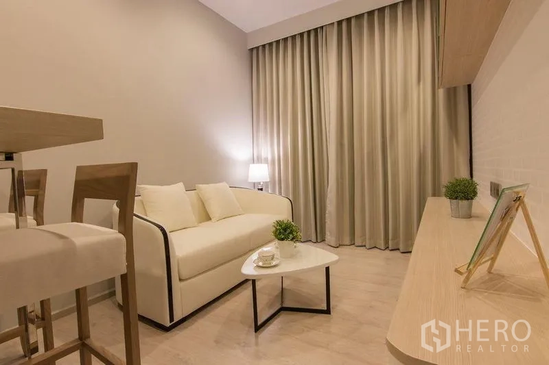 Condominium for sale in Watthana, Bangkok - Cozy living room with neutral decor, sofa, coffee table and media console.