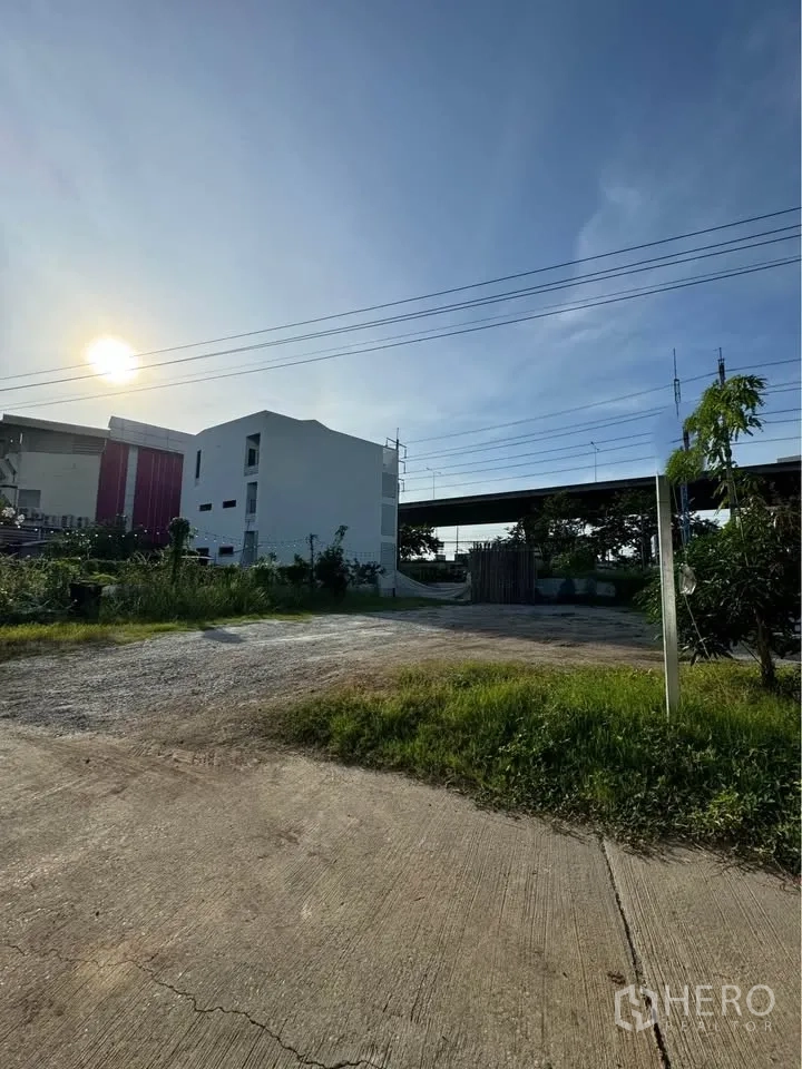 ที่ดิน for rent in Bang Na, Bangkok - ถนนคอนกรีตนำเข้าสู่ที่ดินแปลงเรียบ มีต้นไม้ตามแนวขอบและประตูทางเข้า