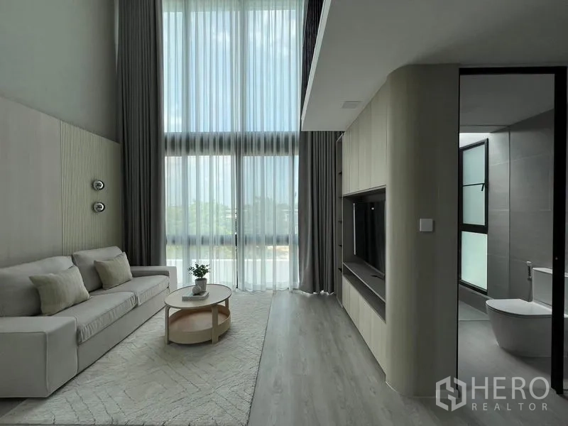 Detached House for rent in Saphan Sung, Bangkok - Living area with double-height sheer curtains, sofa set and access to a bathroom.