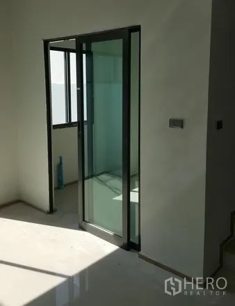 Townhouse for rent in Bueng Kum, Bangkok - Sunlit interior featuring a glass sliding door and window with clean white walls.