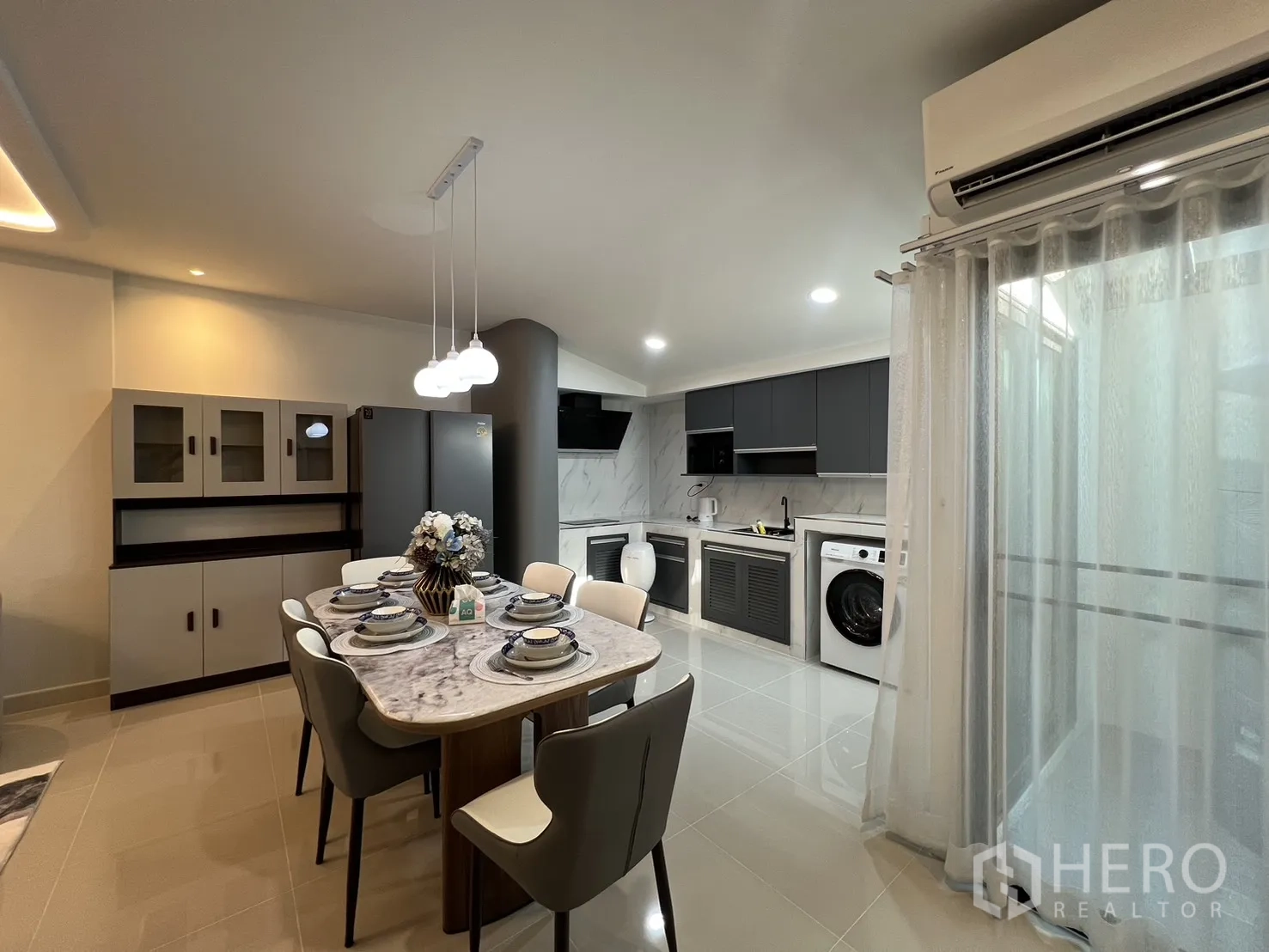联排别墅 for rent in Bang Phli, Samut Prakan - 餐区配三盏吊灯、空调与落地窗帘。