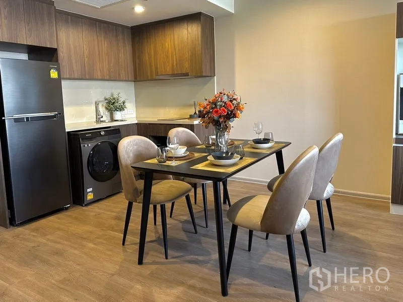 Condominium for rent in Pathum Wan, Bangkok - Kitchen with full-size fridge, washer and a four-seat dining area on wood flooring.