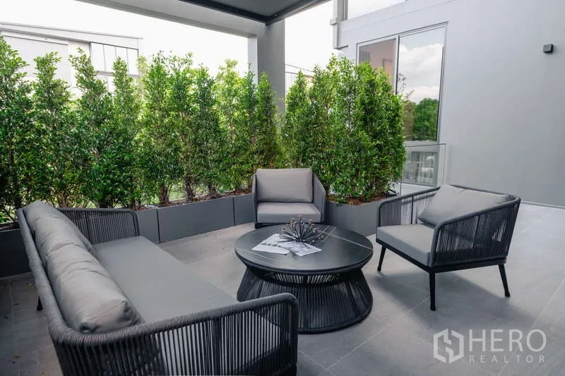 Detached House for rent in Saphan Sung, Bangkok - Covered terrace with outdoor lounge seating and privacy hedges.