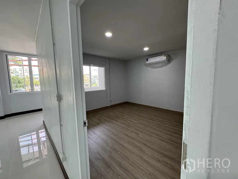 Townhouse for sale in Bueng Kum, Bangkok - Bedroom with wood flooring, window and wall-mounted air conditioner.