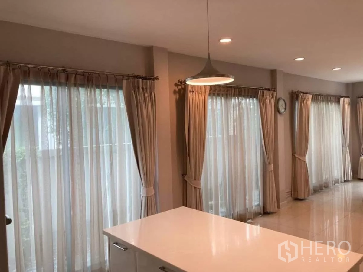 Detached House for rent in Mueang Nonthaburi, Nonthaburi - Kitchen island and rows of tall windows with sheer curtains bringing abundant natural light.