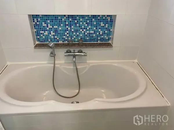 公寓 出售在Phra Khanong, Bangkok - 浴室内置浴缸，手持花洒与蓝色马赛克装饰壁龛。