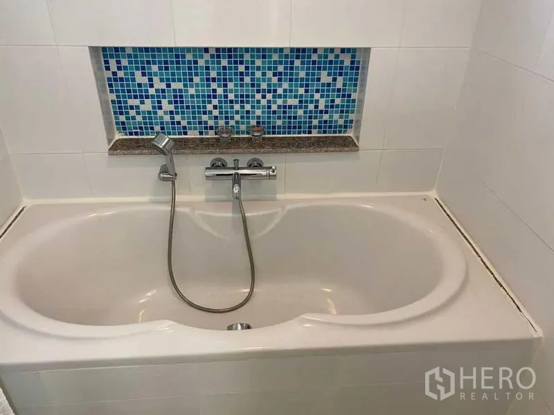 公寓 出售在Phra Khanong, Bangkok - 浴室内置浴缸，手持花洒与蓝色马赛克装饰壁龛。
