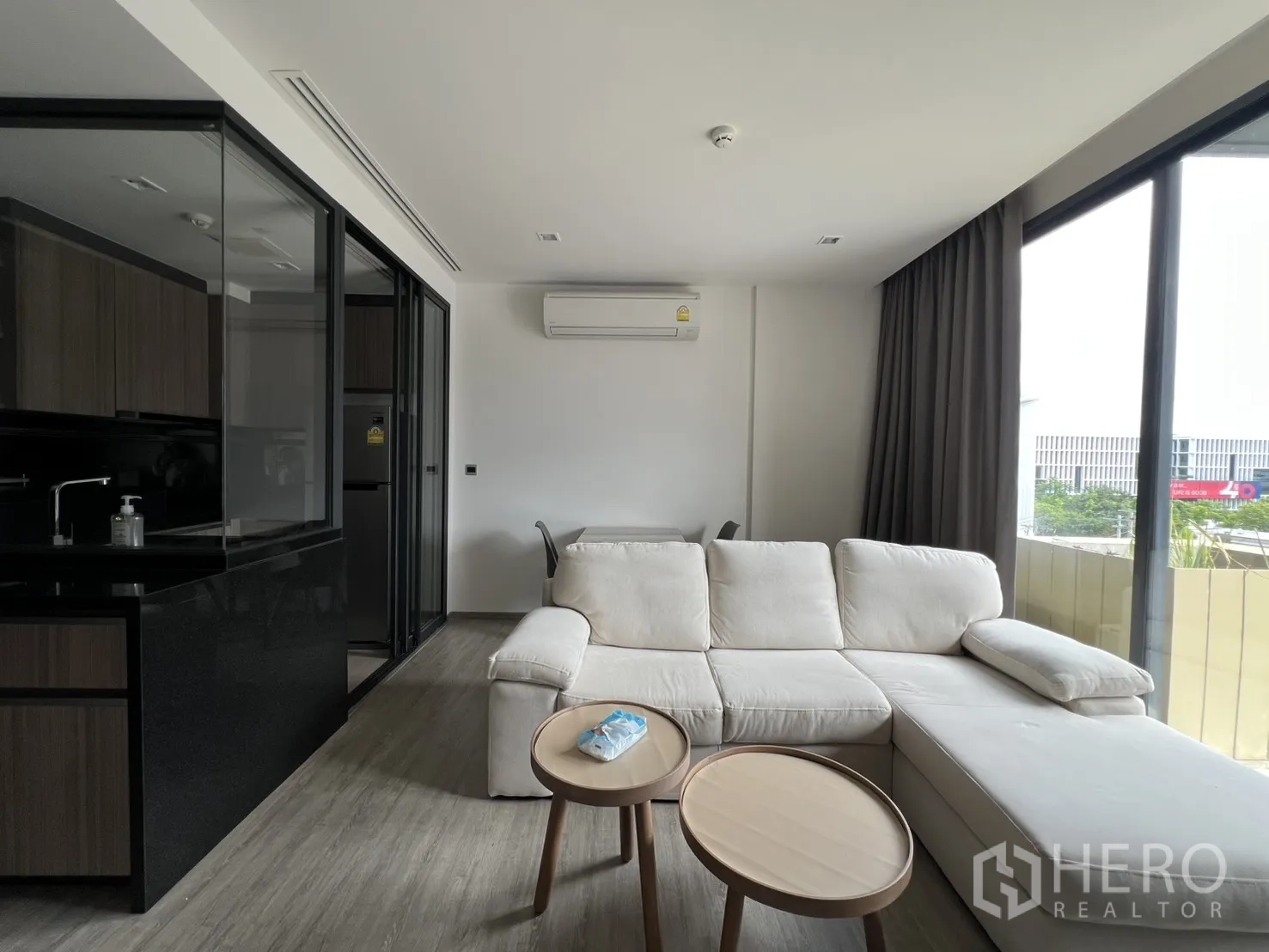คอนโด for rent in Watthana, Bangkok - พื้นที่นั่งเล่นสว่างด้วยโซฟาสีครีม โต๊ะกลางชุด และหน้าต่างบานใหญ่พร้อมผ้าม่าน.