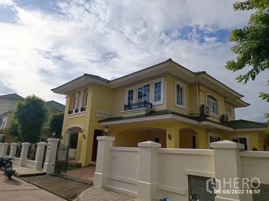บ้าน ขายในPrawet, Bangkok - มุมมองด้านหน้าบ้านเดี่ยวสีเหลืองพร้อมทางเข้ารั้วและที่จอดรถ