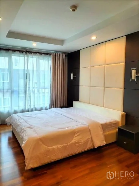 คอนโด ให้เช่าในWatthana, Bangkok - ห้องนอนหลัก ผนังบุซอฟท์แพด หน้าต่างบานใหญ่ และเตียงควีนบนพื้นไม้
