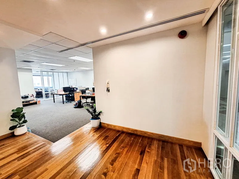 Office Space for rent in Bang Na, Bangkok - Entrance foyer with polished wooden flooring leading into a bright open‑plan office with carpet and potted plants.