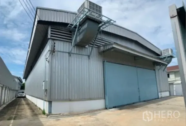 Warehouse for rent in Suan Luang, Bangkok - Angle view of steel warehouse exterior with large gates and off-street loading area.