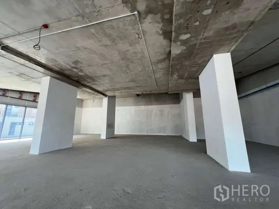 Retail Space for rent - Unfitted retail unit with exposed concrete ceiling, white structural columns and an open-plan floor.