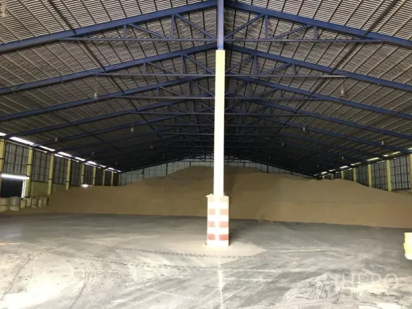 Warehouse for rent in Phra Nakhon Si Ayutthaya - Spacious warehouse interior with steel truss roof, skylights and bulk storage piles on polished concrete floor.