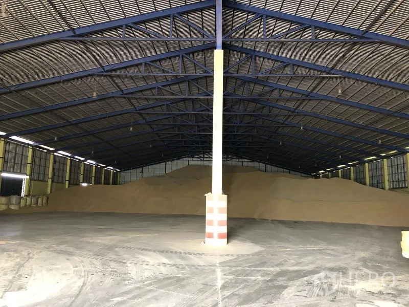 Warehouse for rent in Phra Nakhon Si Ayutthaya - Spacious warehouse interior with steel truss roof, skylights and bulk storage piles on polished concrete floor.