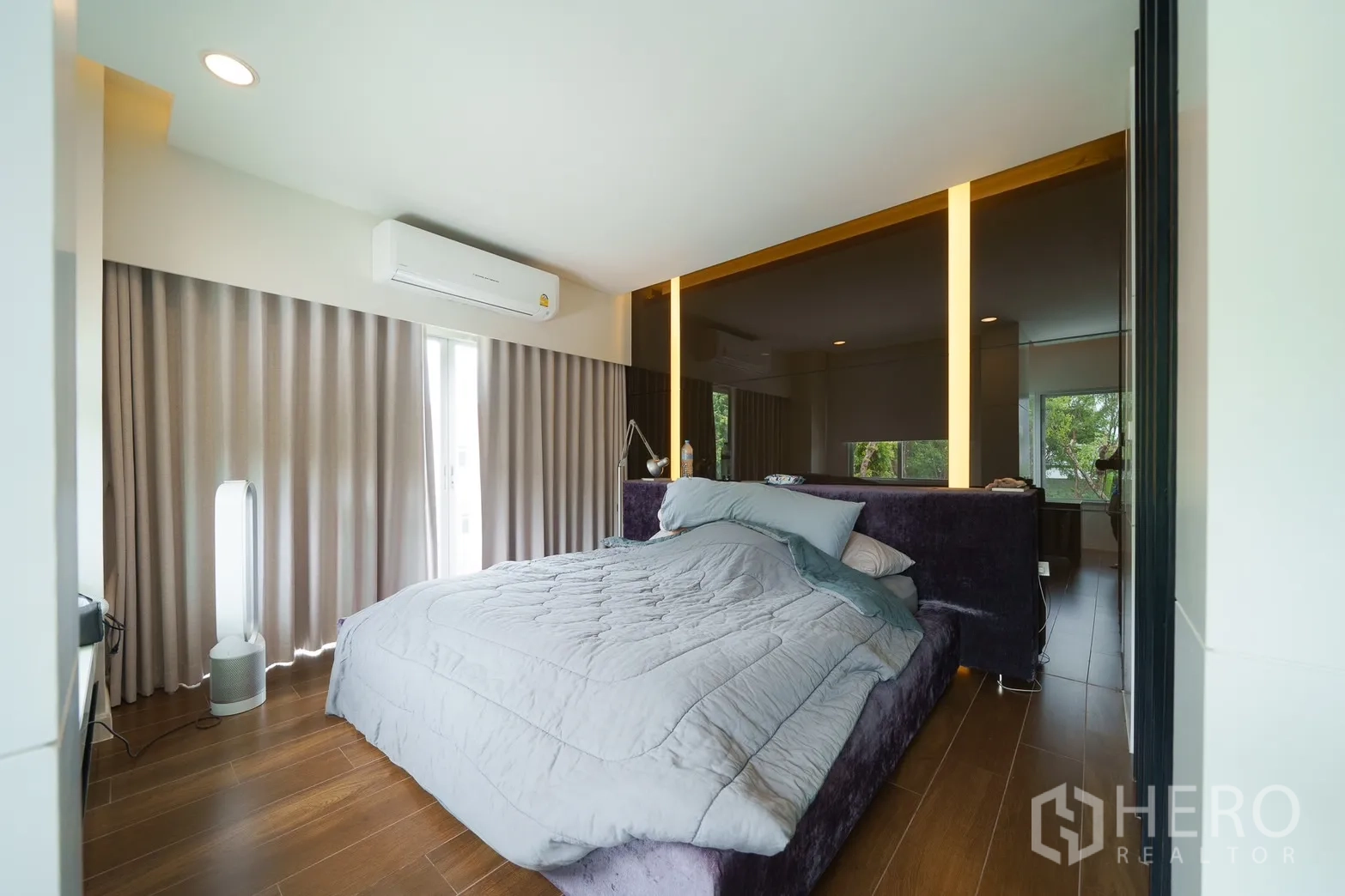 Detached House for rent or sale in Saphan Sung, Bangkok - Primary bedroom with wood flooring, upholstered bed, full‑height curtains and split‑type air conditioner.