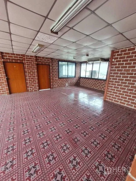 Warehouse for rent in Bang Yai, Nonthaburi - Corner office with brick-pattern walls, two wooden doors and patterned tiles.