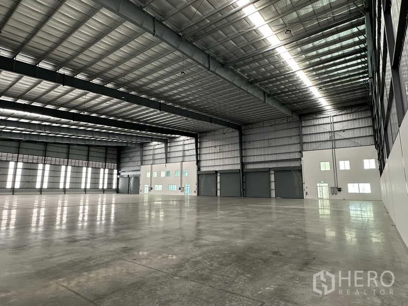 Factory for rent in Bang Sao Thong, Samut Prakan - Factory interior looking toward office block and loading doors under high roof.