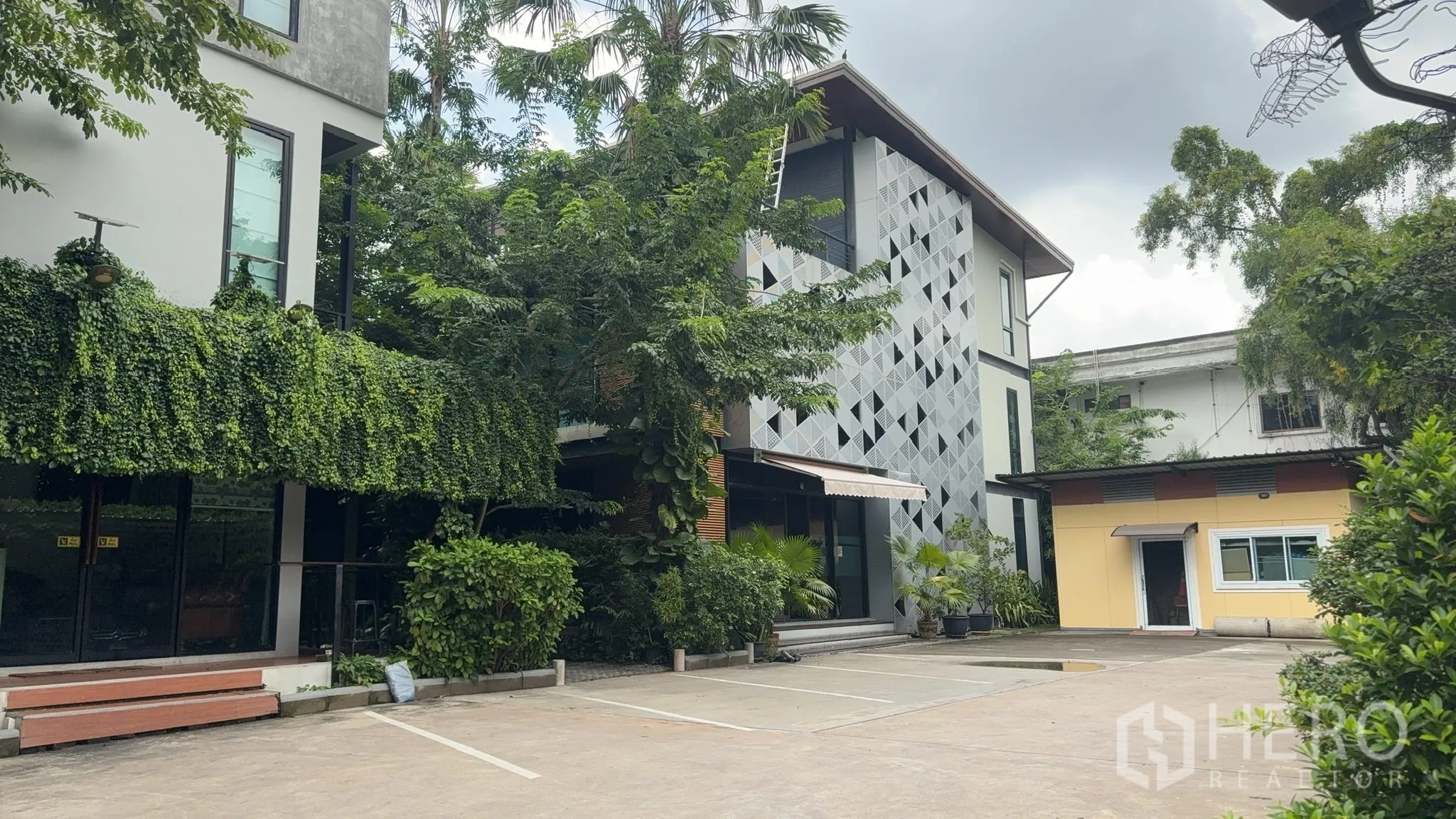 สำนักงาน ให้เช่าในKhlong Toei, Bangkok - ด้านหน้าอาคารสำนักงานสมัยใหม่ พร้อมฟาซาดลายเรขาคณิตและที่จอดรถส่วนตัวหลายคัน