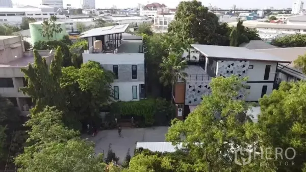 Office Space for rent in Khlong Toei, Bangkok - Aerial view of a modern low-rise office compound with a rooftop terrace surrounded by mature trees in Bangkok.