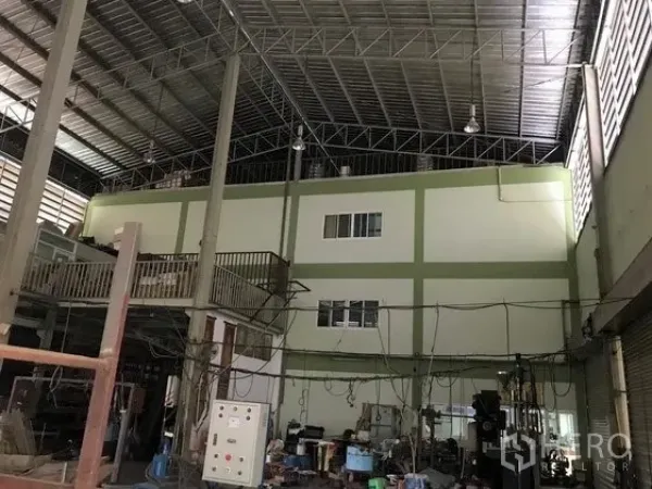 Factory for sale in Khlong Luang, Pathum Thani - High‑ceiling factory hall with steel trusses, mezzanine office block and machinery.