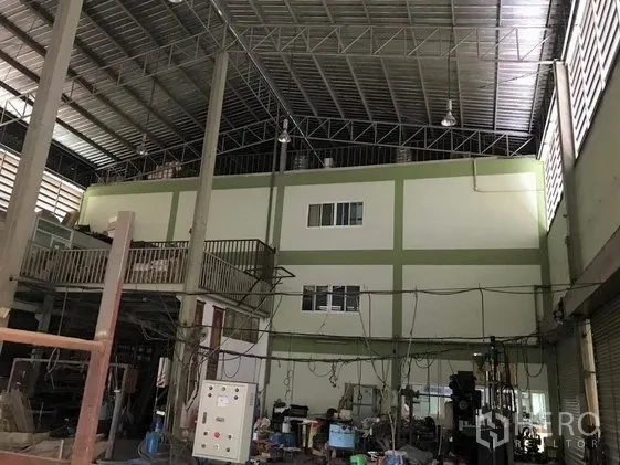 Factory for sale in Khlong Luang, Pathum Thani - High‑ceiling factory hall with steel trusses, mezzanine office block and machinery.