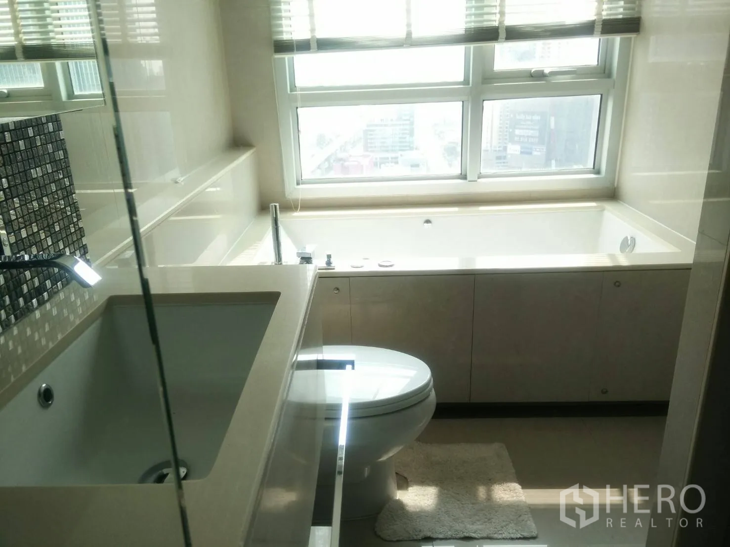 คอนโด ให้เช่าในRatchathewi, Bangkok - ห้องน้ำสมัยใหม่พร้อมอ่างอาบน้ำข้างหน้าต่าง โถสุขภัณฑ์ และเคาน์เตอร์ล้างหน้ากระเบื้องโมเสก