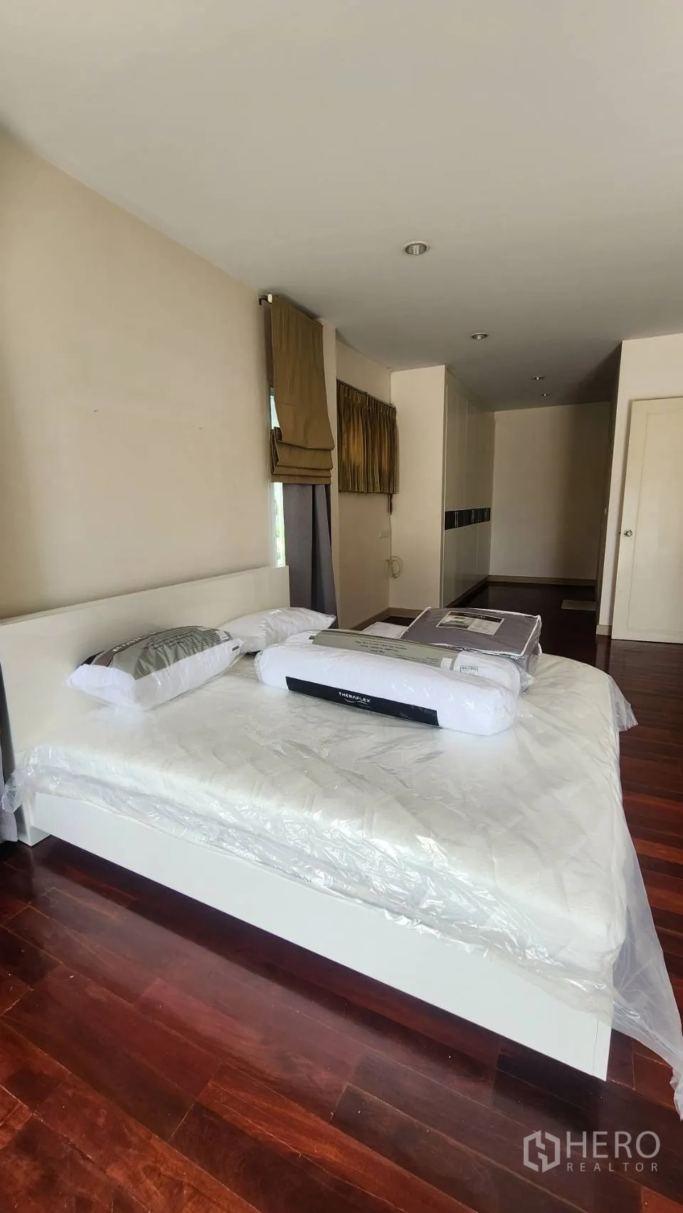 Detached House for rent in Watthana, Bangkok - Spacious bedroom with wood floors and large bed.