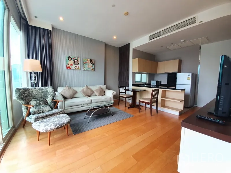 Condominium for rent in Chatuchak, Bangkok - Bright living room with sofa, accent armchair, floor lamp, glass coffee table and open kitchen on wood floors.