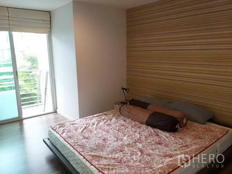公寓 出租在Watthana, Bangkok - 主卧配大窗与条纹背景墙，推拉门连接阳台。