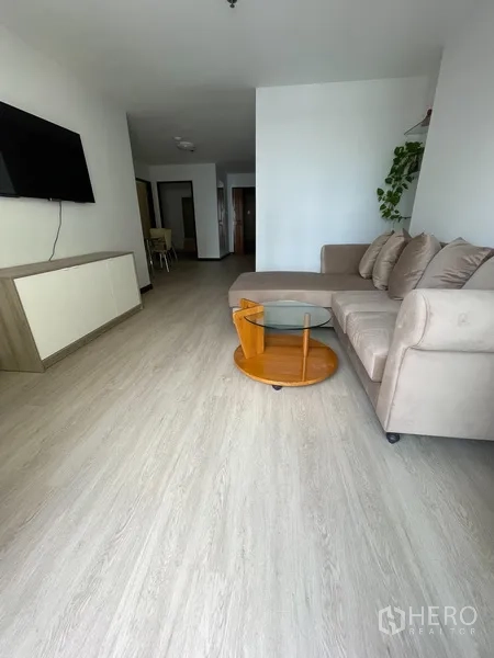 Condominium for rent or sale in Watthana, Bangkok - Open-plan living space with sofa, TV console and dining zone in the back.