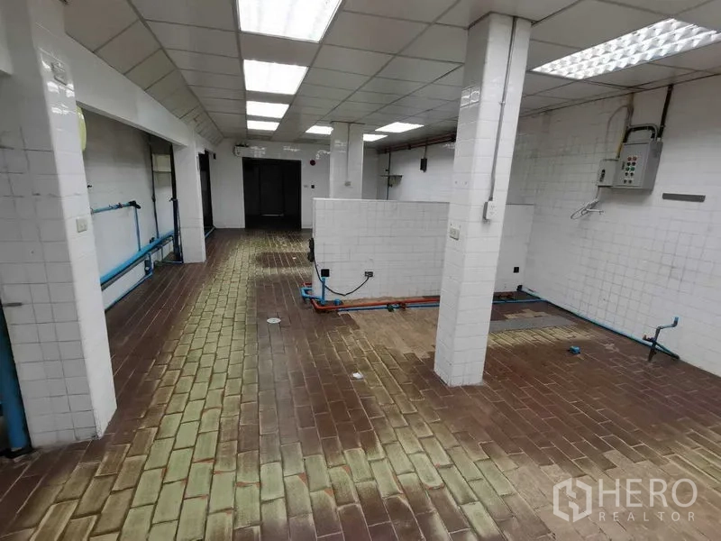 Retail Space for rent in Pathum Wan, Bangkok - Back-of-house tiled room with brick flooring and exposed plumbing for a commercial kitchen.
