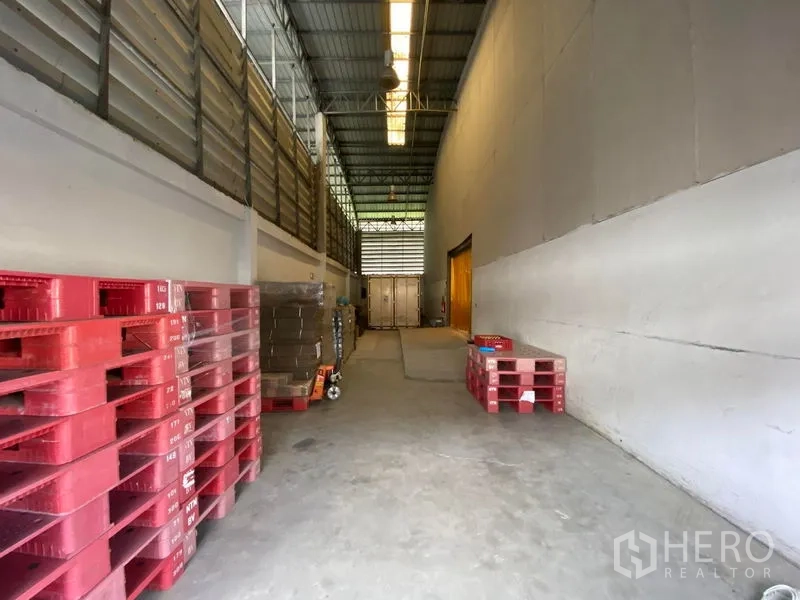 Warehouse for rent in Bueng Kum, Bangkok - Covered loading bay with stacked pallets and access to storage and dock area for trucks.