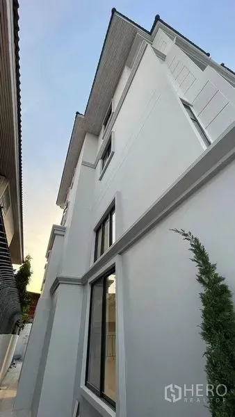 Townhouse for sale in Prawet, Bangkok - Modern white townhouse exterior with large windows and a gable roof.
