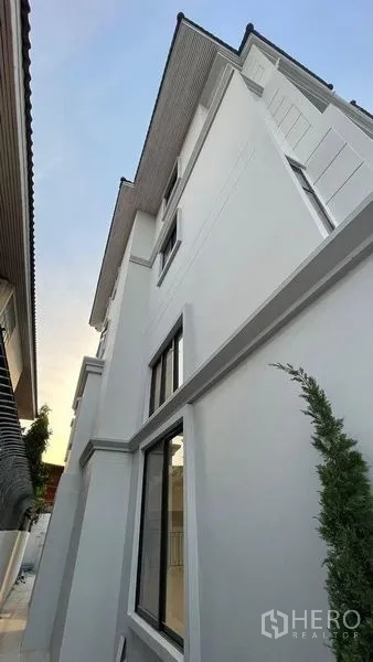 Townhouse for sale in Prawet, Bangkok - Modern white townhouse exterior with large windows and a gable roof.