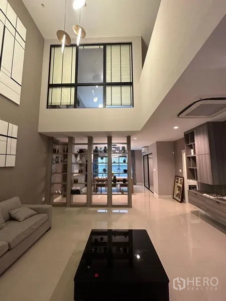 联排别墅 出售在Saphan Sung, Bangkok - 开放式起居区，展示柜、电视墙与通往二层的楼梯。