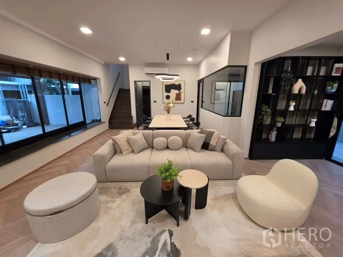 Townhouse for rent in Bang Phli, Samut Prakan - Wide view of living space with staircase, large windows, dining set, and black display shelves.