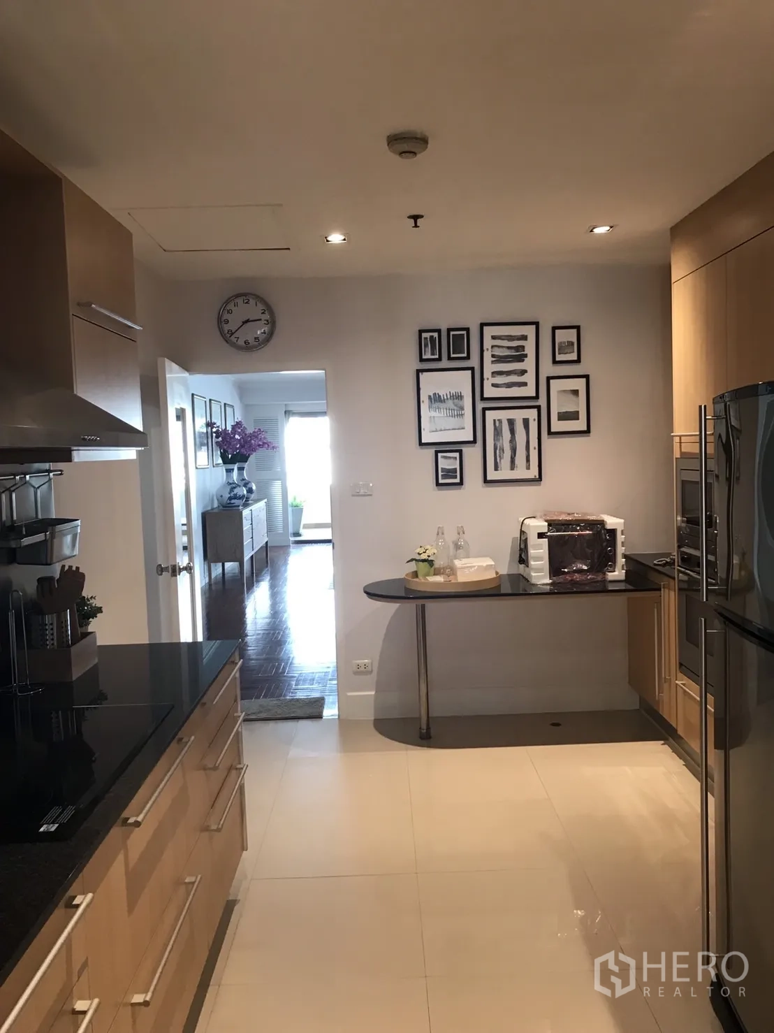 Condominium for rent in Bangkok - Modern kitchen with light wood cabinetry, black stone countertops and a small breakfast ledge.