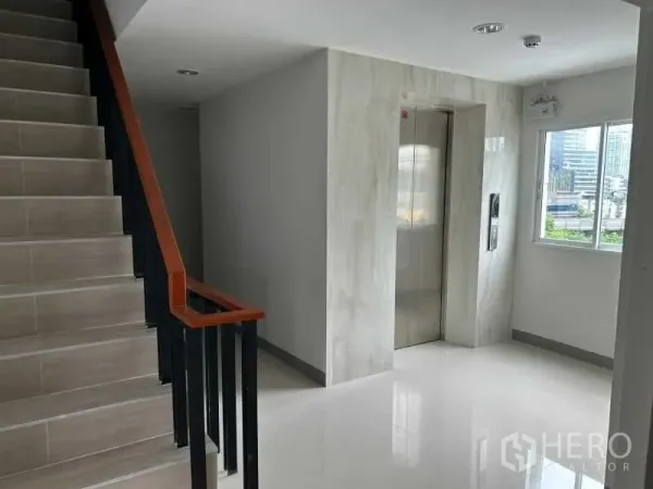 Office Space for rent in Bang Rak, Bangkok - Lift lobby with marble-look walls beside a stairway and a bright window.