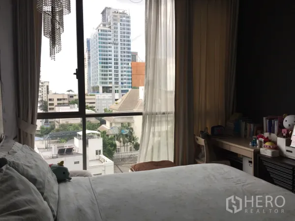 คอนโด ขายในWatthana, Bangkok - ห้องนอนอบอุ่นพร้อมเตียง โต๊ะทำงาน ผ้าม่านโปร่ง และหน้าต่างเต็มผนังมองเห็นวิวเมือง