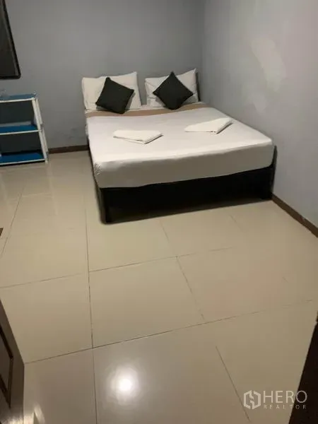 Retail Space for rent in Khlong Toei, Bangkok - Simple bedroom with double bed, tiled floor and open shelving.
