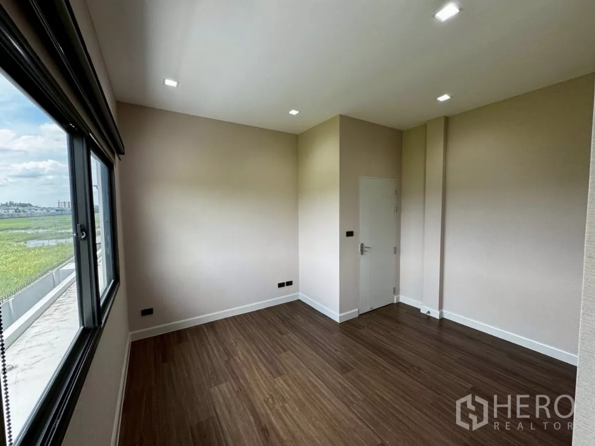 独立式住宅 出租或出售在Lat Krabang, Bangkok - 明亮次卧，宽窗采光充足，木地板，可眺望周边绿地。