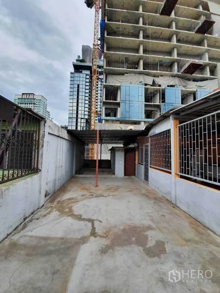 Shophouse for rent in Watthana, Bangkok - Rear concrete yard with partial roof beside nearby high-rise construction.