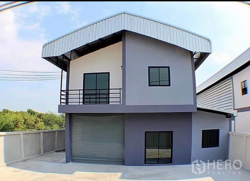 Factory for rent in Lat Lum Kaeo, Pathum Thani - Front view of a modern factory facade with large roller shutter, balcony and perimeter wall.