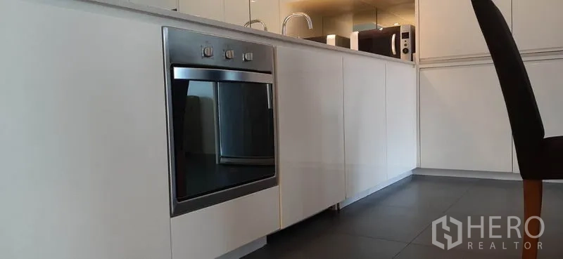 Condominium for rent in Phaya Thai, Bangkok - Close-up of built-in stainless-steel oven and white base cabinets in a modern kitchen.