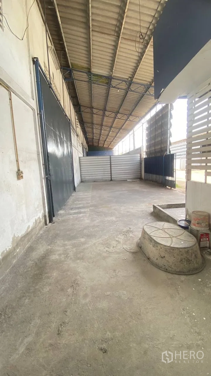 工厂 for rent in Bang Phli, Samut Prakan - 侧面有雨棚的装卸区，配金属栅栏与大型滑动门。