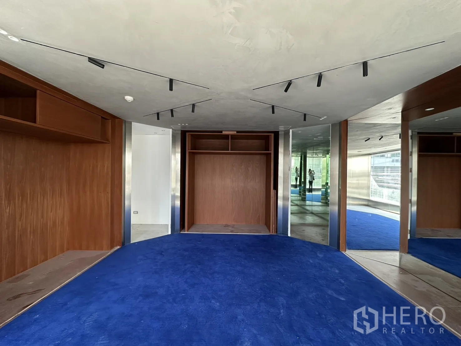พื้นที่ขายของ for rent in Watthana, Bangkok - ชั้นบนสไตล์โชว์รูม ปูพรมสีน้ำเงิน มีตู้ไม้และกระจกเงาพร้อมไฟราง.