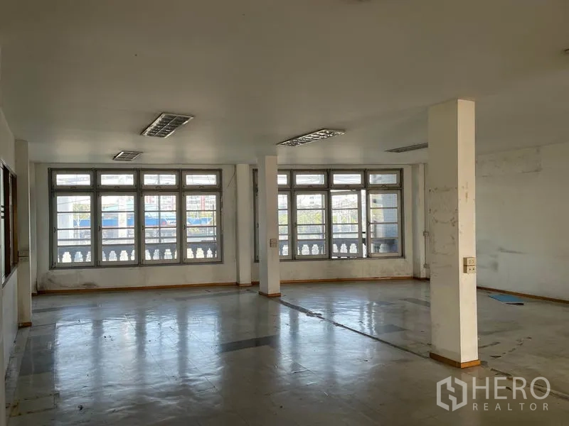 Warehouse for rent in Prawet, Bangkok - Large open-plan office floor with rows of wide windows and structural columns.