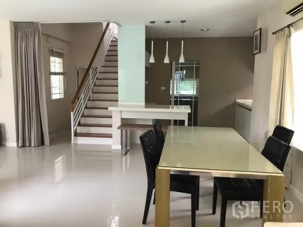 独立式住宅 出租在Khlong Sam Wa, Bangkok - 餐桌区面向楼梯，吊灯与备餐台相连。